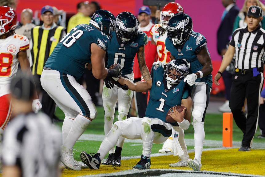 Philadelphia players help quarterback Jalen Hurts up after a score in the Super Bowl.
