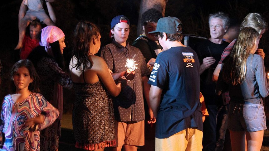 Kids lighting sparklers at night