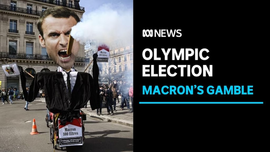Olympic Election, Macron's Gamble: A dummy of Emmanuel Macron at a protest with a large false cigarette smoking in his mouth.