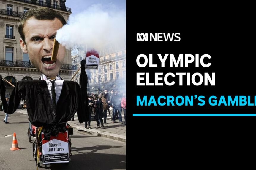 Olympic Election, Macron's Gamble: A dummy of Emmanuel Macron at a protest with a large false cigarette smoking in his mouth.