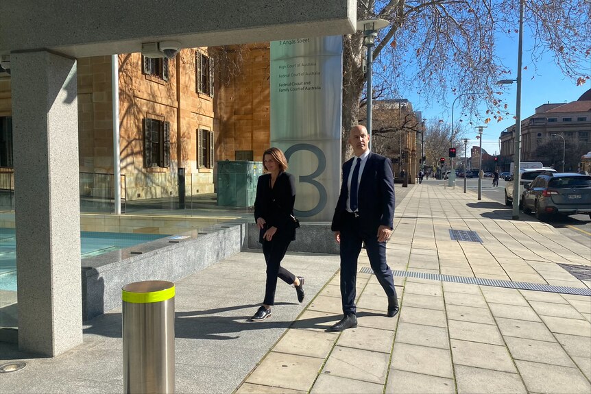 a woman and man walk towards federal court dressed smart.