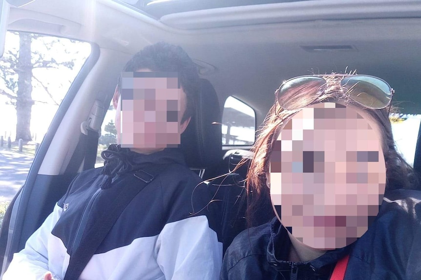 Two young people, faces blurred, in a car.
