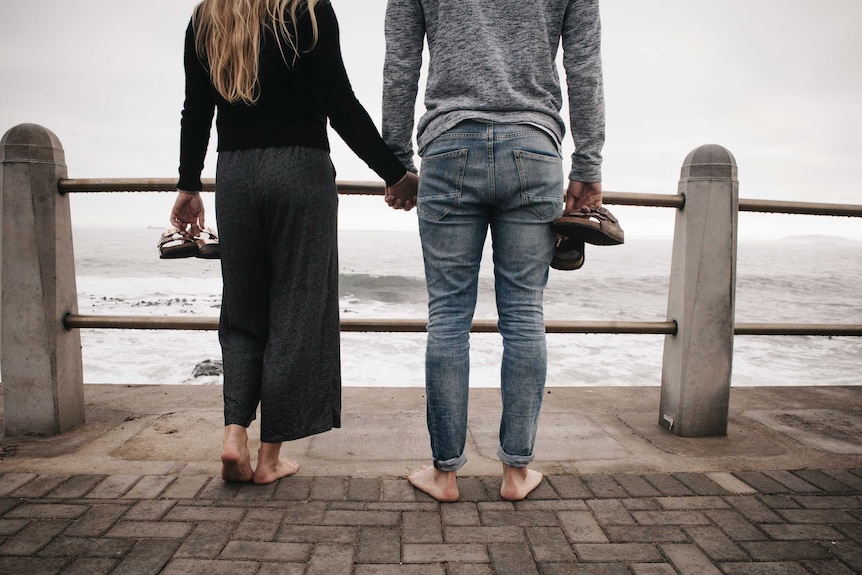 Woman and man hold hands overlooking the water
