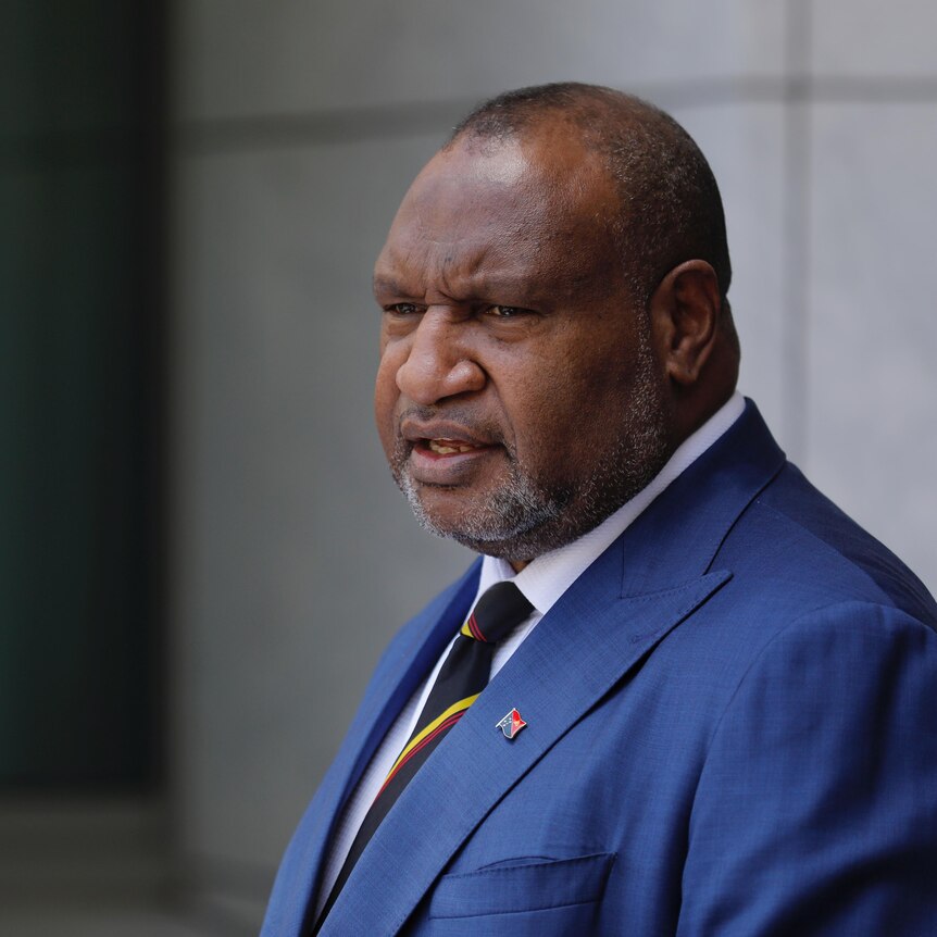 James Marape, wearing a navy blue suit with pin on the collar