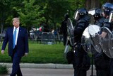 President Donald Trump walks past police in riot gear on his way across Lafayette Park to St John's Church after protests.