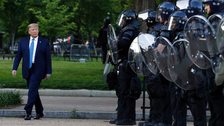 President Donald Trump walks past police in riot gear on his way across Lafayette Park to St John's Church after protests.