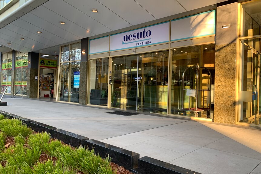 The front entrance of a hotel, with sliding doors, and a sign that says Nesuto.