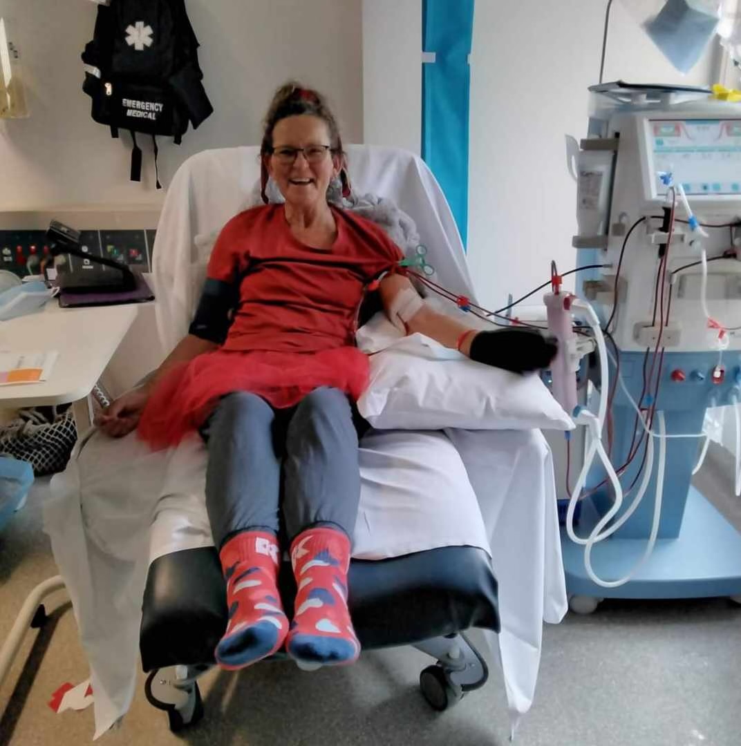 Joanne sits in a hospital chair recieving IV fluid wearing red clothing