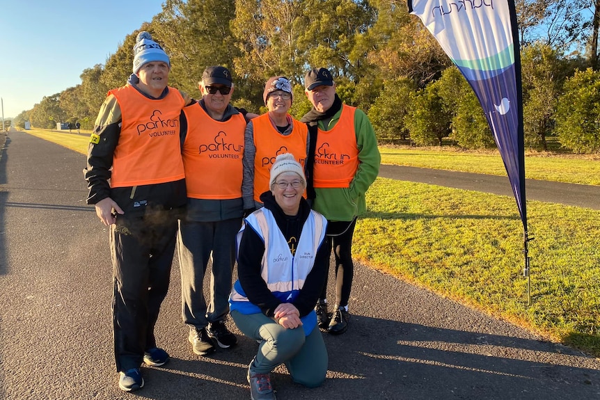 A group of people with high vis vests and winter clothes smile at the camera 