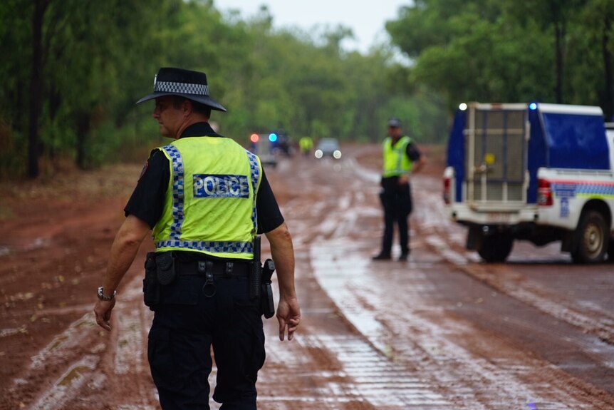 Police officers and cars on a gravel road