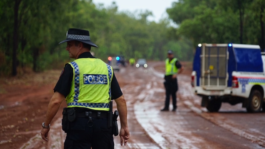 Police officers and cars on a gravel road