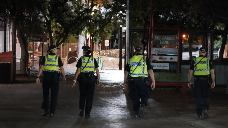 the backs four police officers walking in a dark street
