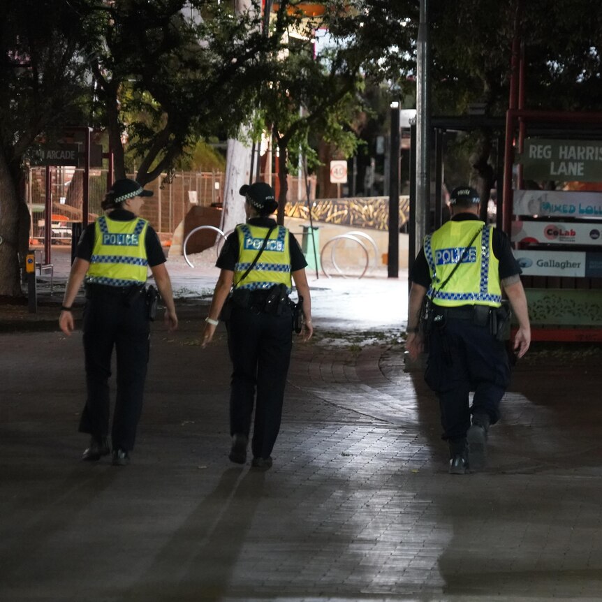 the backs four police officers walking in a dark street