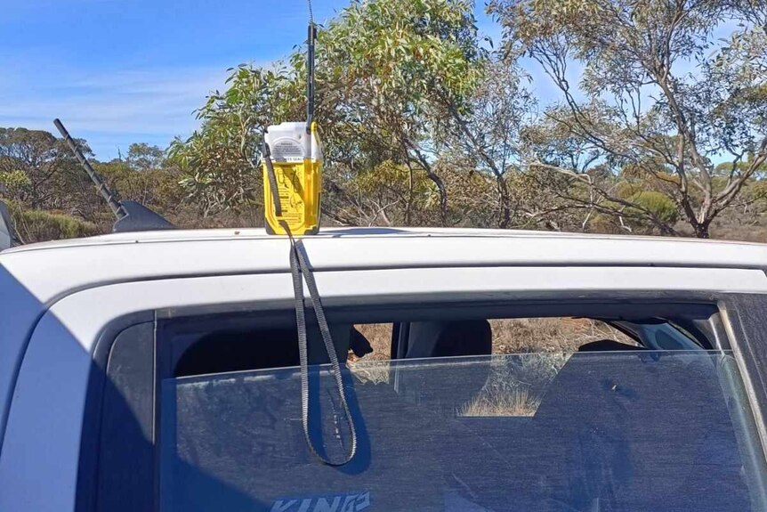A bright-coloured device that looks like a walkie-talkie sits on the roof of a vehicle in the outback.