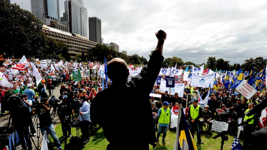 A speaker thrusts his arm into the air as thousands of unionists look on at the Domain in Sydney