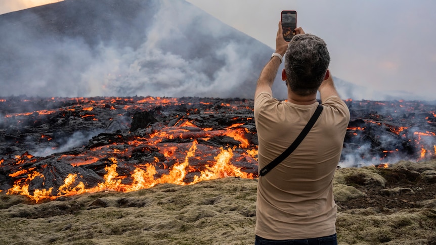 Man stands with phone in front of erupting Iceland volcano 