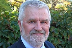 A man with grey hair and a beard wearing a suit and tie