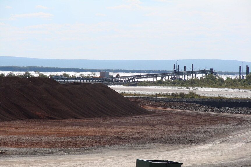 A conveyor belt over a bleak-looking mine site.
