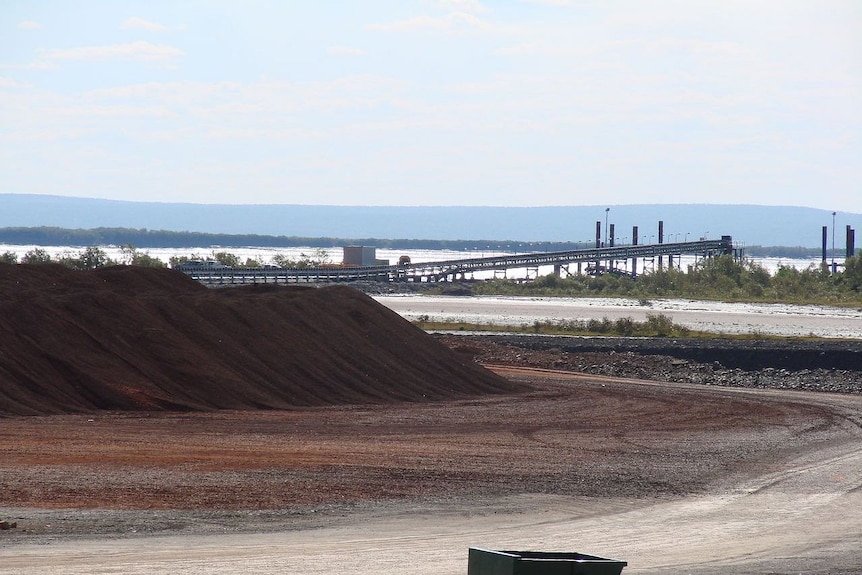 A conveyor belt over a bleak-looking mine site.