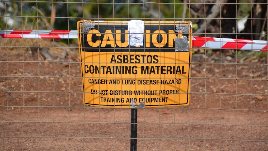 Wire fence covering a sign warning about asbestos contamination