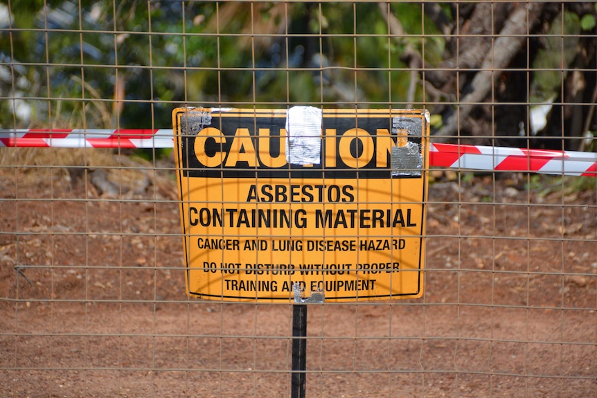Wire fence covering a sign warning about asbestos contamination
