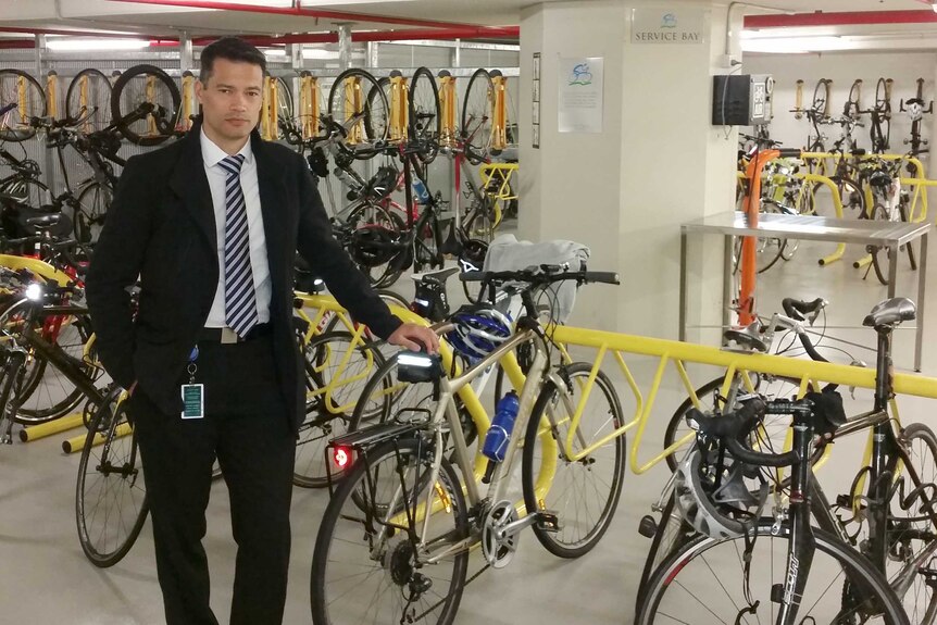 Peter Mah stands in a bike shop next to a rack of bikes wearing a suit.