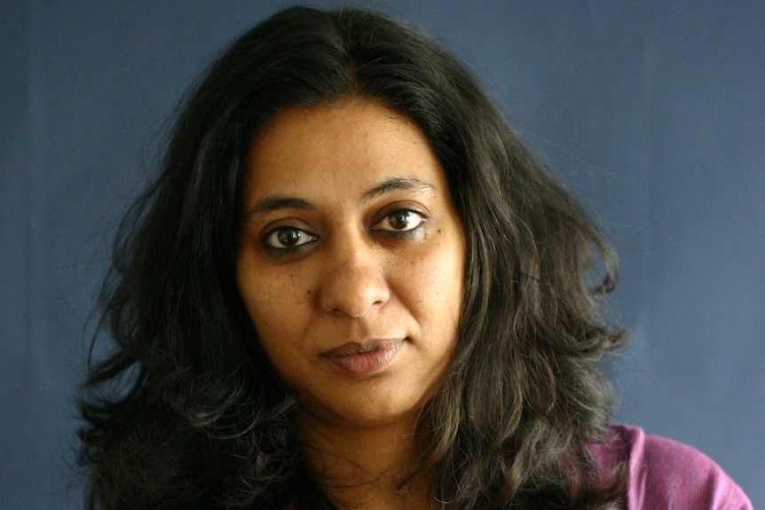 A woman poses for a photo in front of a blue background