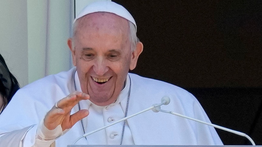 Pope Francis appears on a hospital balcony in Rome wearing white.