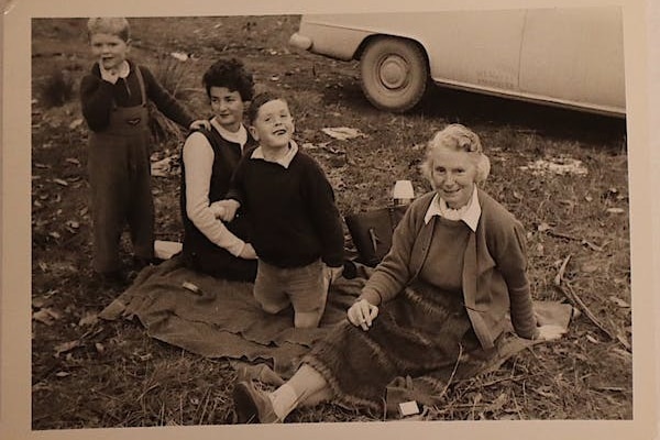 A black and white image of an older woman with another woman and two young boys. 