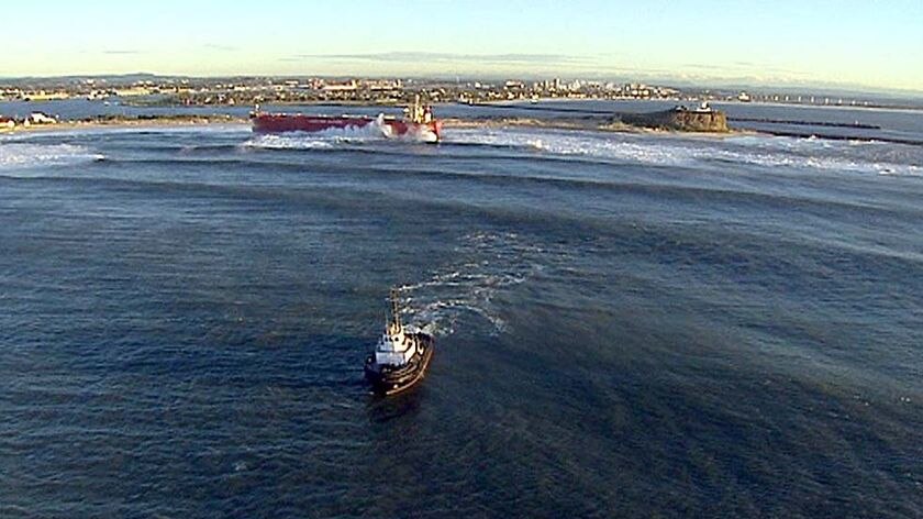 Breaking point: A tugboat sits off Nobbys Beach with the Pasha Bulker behind