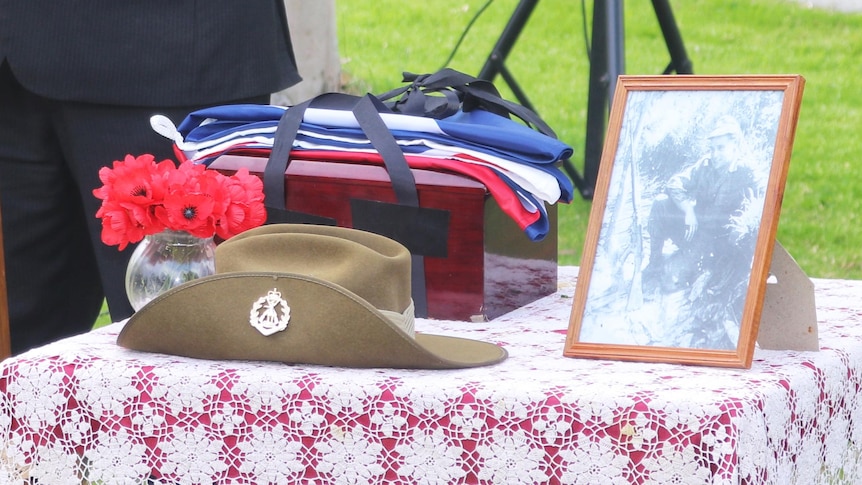 Paul Altimore standing at a lecturn delivering a speech next to table with photo of Private Halliday and other personal objects