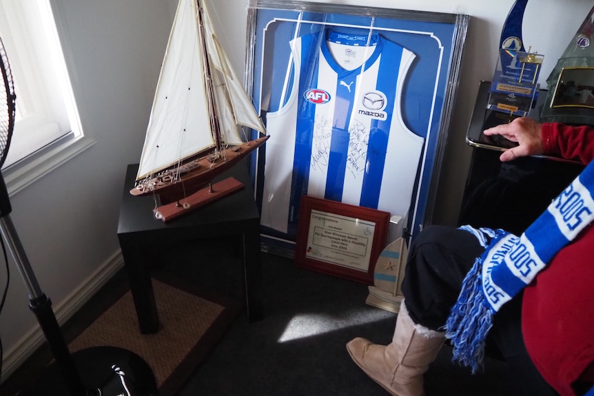 A blue and white football guernsey in a frame and a model sailing boat.