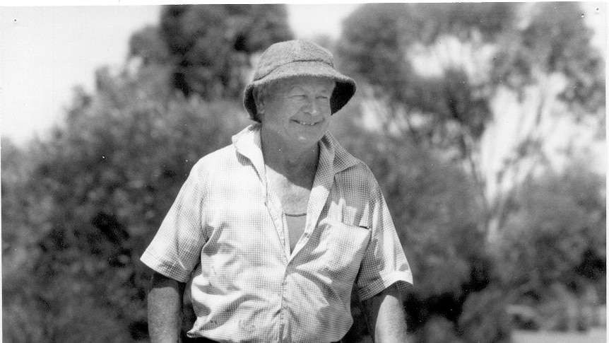 A black and white image of a smiling man in a bucket hat and a flannel t-shirt.