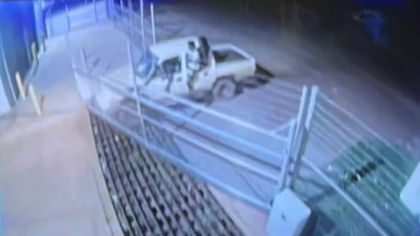 A ute pushing into a front gate of a police station.