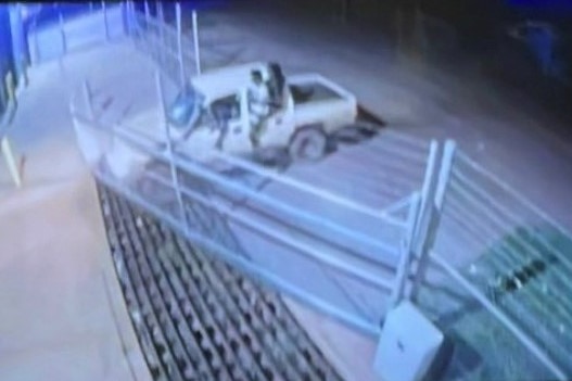 A ute pushing into a front gate of a police station.