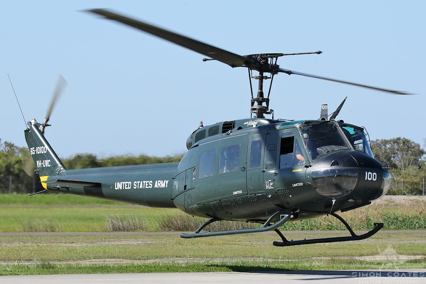 a military style helicopter hovering just above the ground