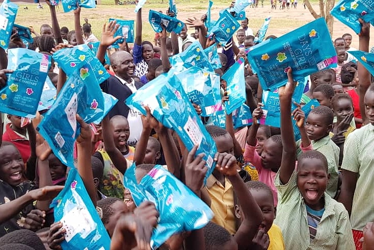 Ugandan teenage girls holding blue 'Days for Girls' packs.