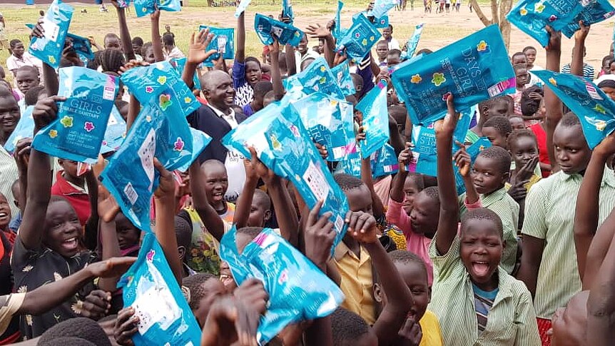 Ugandan teenage girls holding blue 'Days for Girls' packs.
