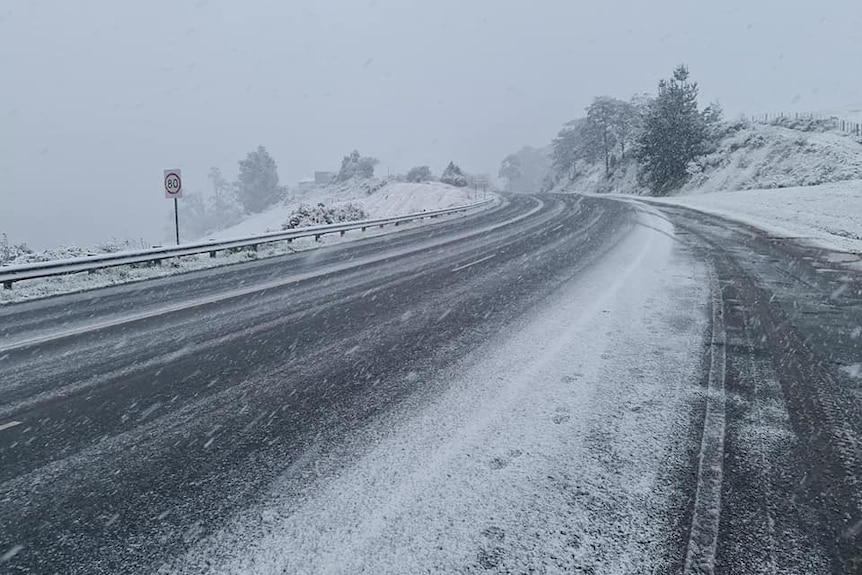 An empty highway with snow settling on either side