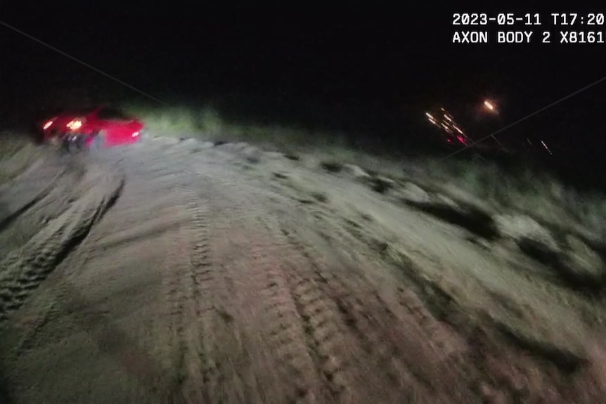 A screenshot of a police body cam video of a car at the end of a dirt road