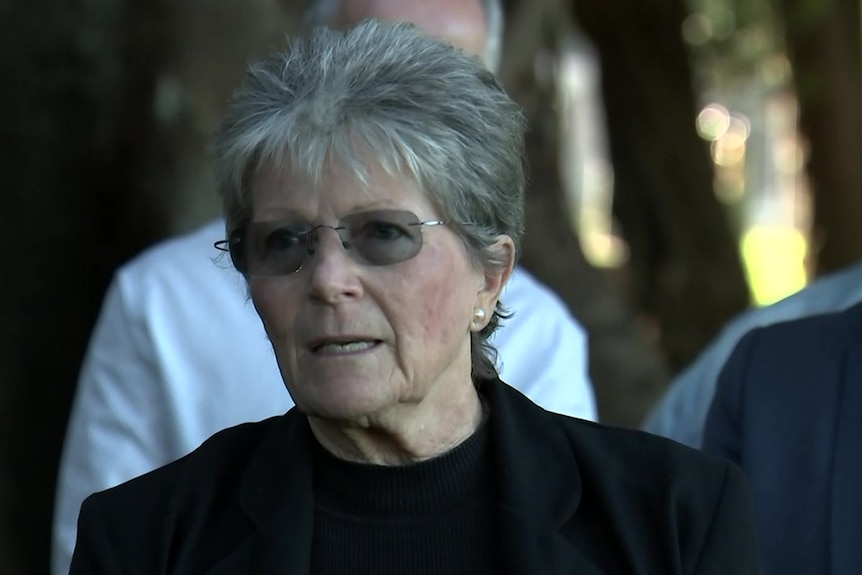 An older woman speaks at a news conference. 