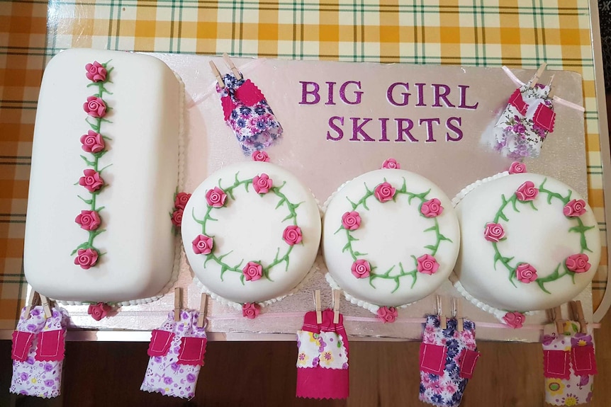 A rectangle cake and three round cakes, white and decorated with roses.