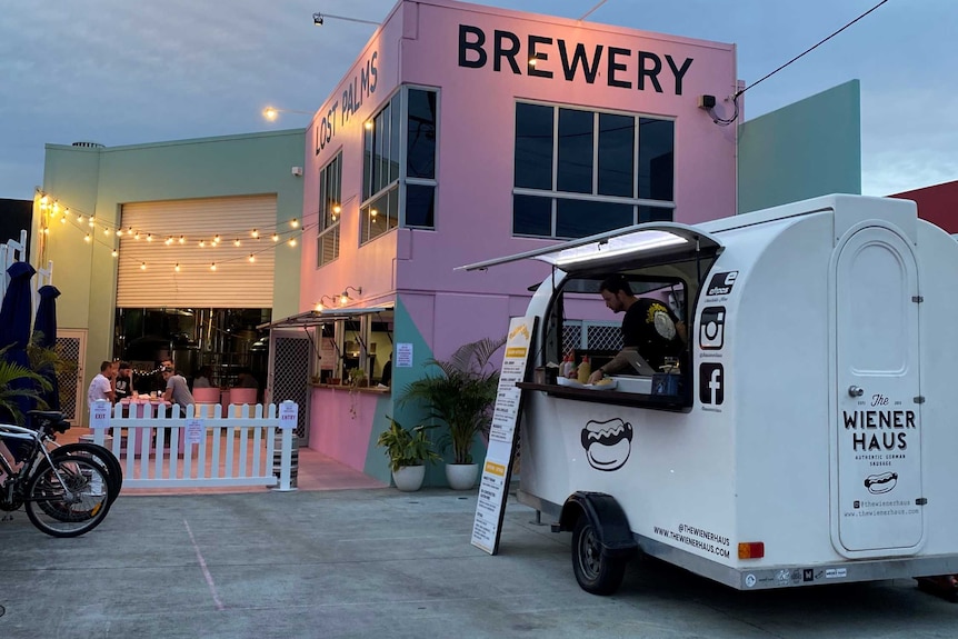 Early evening shot of a pink building with a food truck in foreground.