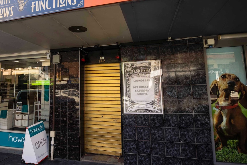 Rolladoor entrance sandwiched between shopfronts on a Hobart street.