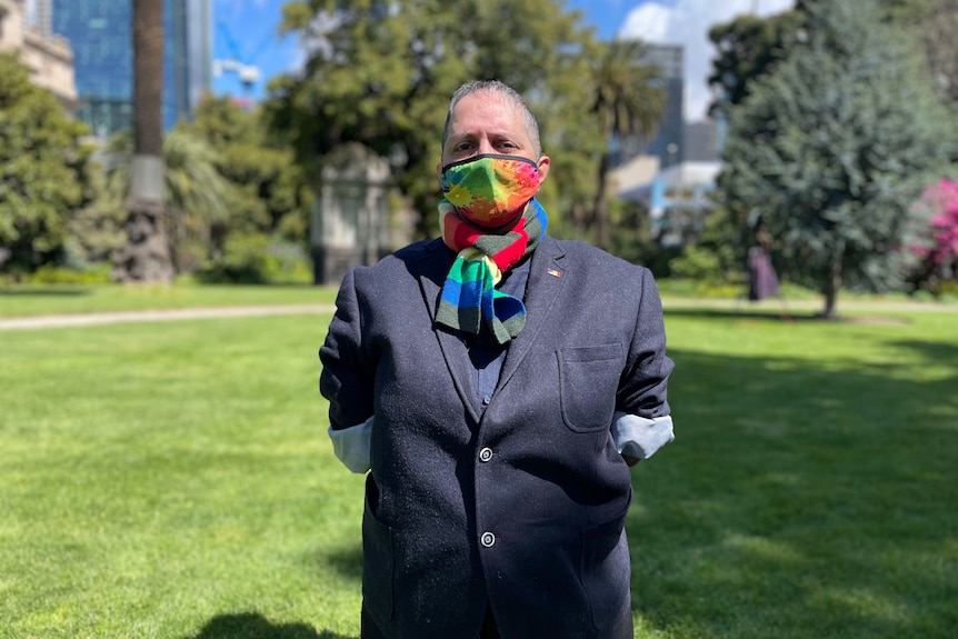 A woman with close-cropped hair stands with a rainbow-coloured mask on her face in a garden. Ausnew Home Care, NDIS registered provider, My Aged Care
