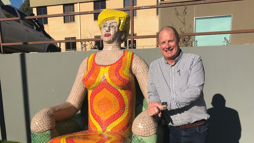 A man with a colourful mosaic sculpture.