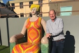 A man with a colourful mosaic sculpture.