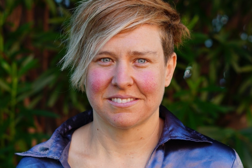 A profile image of Matilda Alexander in a purple shirt standing in front of bushes