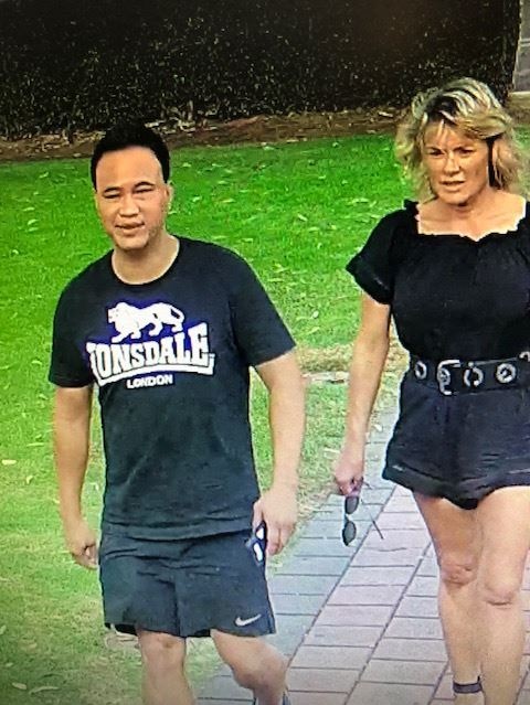 Close up of CCTV footage showing a man and a woman both wearing black walking outside a venue.