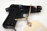 A Beretta snub pistol with string and a cardboard identification tag attached.